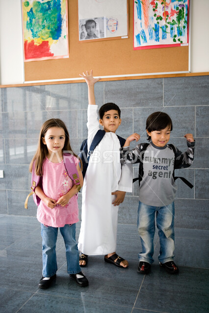 النظر إلى الكاميرا بإيماءات السعادة والحماس بالعودة إلى المدرسة, الاستعداد للعام الدراسي الجديد, تلاميذ عرب خليجيون إماراتيون يرتدون حقيبة الظهر المدرسية, المدارس الأكاديمية في الإمارات العربية المتحدة, صورة الجسم بالطول الكامل