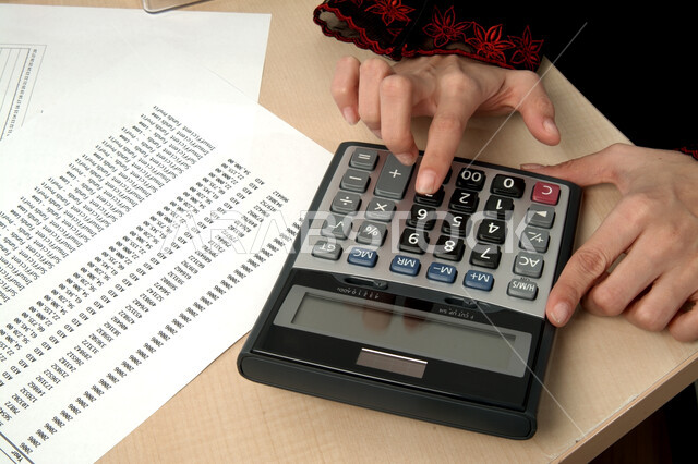 توفير الوقت والجهد في العمل, تنظيم وإدارة الشؤون المالية, حساب التكاليف والارباح والخسائر, إجراء الحسابات والعمليات الرياضية بسرعة ودقة , صورة مقربة ليد إمرأة عربية خليجية اماراتية تقوم باستخدام الآلة الحاسبة في الاعمال