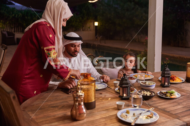 أصناف المأكولات الاماراتيه التقليديه، الإستمتاع بتناول الإفطار الرمضاني مع الأسره، روحانيات رمضانيه وأجواء دينيه، عائله عربيه خليجيه إماراتيه تجلس على مائده الطعام خارج المنزل، مفهوم الأسره الاماراتية السعيده.