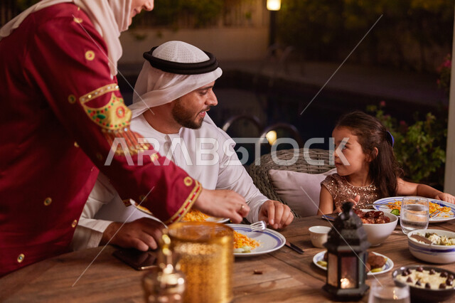الإستمتاع بتناول الإفطار الرمضاني مع الأسره، روحانيات رمضانيه وأجواء دينيه، عائله عربيه خليجيه إماراتيه تجلس على مائده الطعام خارج المنزل، مفهوم الأسره الاماراتية السعيده، أصناف المأكولات الاماراتيه التقليديه. 