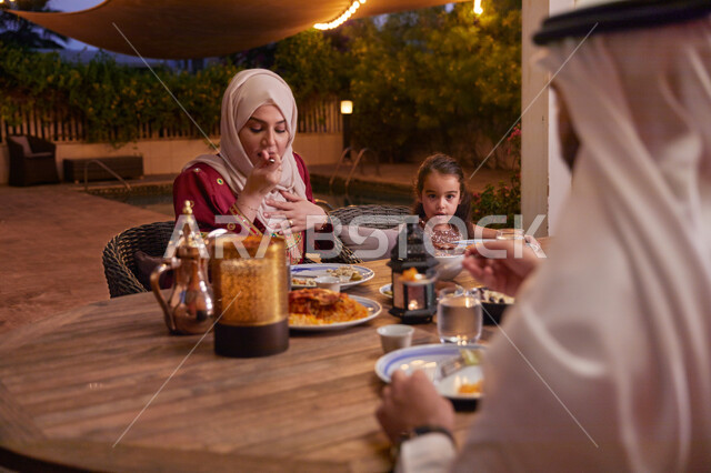 ديكورات وأجواء رمضانيه، كسر الصيام عند سماع أذان المغرب، قضاء أوقات ممتعه مع العائله في الخارج، أسرة عربيه خليجيه اماراتية تقوم بتناول الطعام العائلي في أحد المطاعم، مائدة إفطار مليئه بالأصناف والمأكولات الشهية.