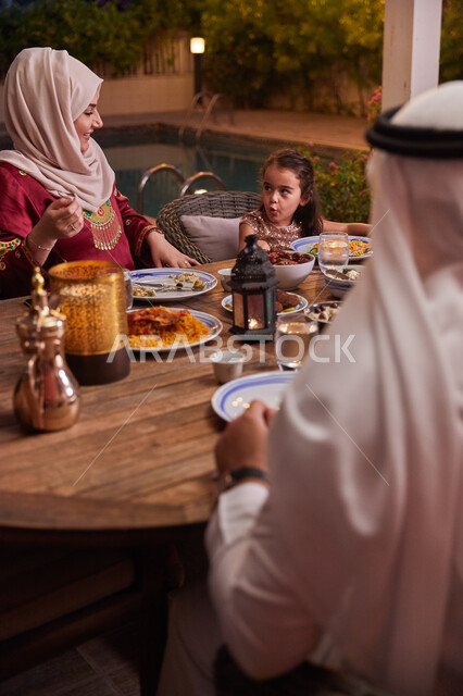 كسر الصيام عند سماع أذان المغرب، قضاء أوقات ممتعه مع العائله في الخارج، أسرة عربيه خليجيه اماراتية تقوم بتناول الطعام العائلي في أحد المطاعم، مائده إفطار مليئه بالأصناف والمأكولات الشهية، ديكورات وأجواء رمضانيه.