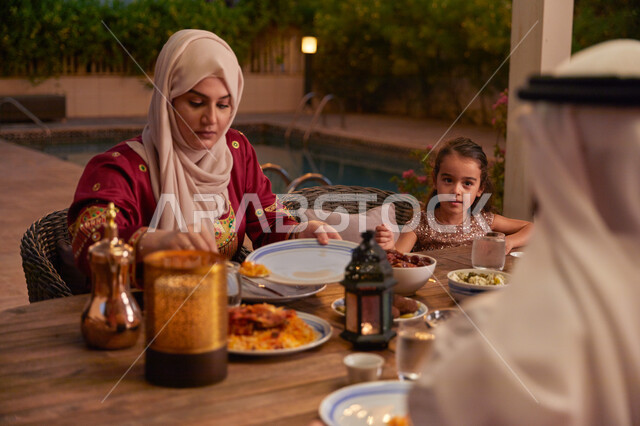 رمضان شهر الخير والبركة، المأكولات والمقبلات الرمضانيه المتنوعه والشهية، اجتماع الأهل ومشاركة الطعام على مائده الإفطار، عائله عربيه خليجيه اماراتية تقوم بتناول الفطور في الخارج، مطعم مزين بالديكورات الرمضانية.