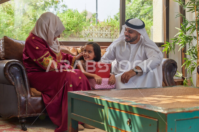 المكافآت والجوائز في الأعياد والمناسبات، تقديم الهدايا والمفاجآت للأطفال، زوجان عربيان خليجيان اماراتيان يقومان بإعطاء هدية لإبنتهم بمناسبة عيد ميلادها، حسن المعاملة وتربيه الأبناء في الإسلام، ادخال الفرحة والسرور إلى قلب البنات.