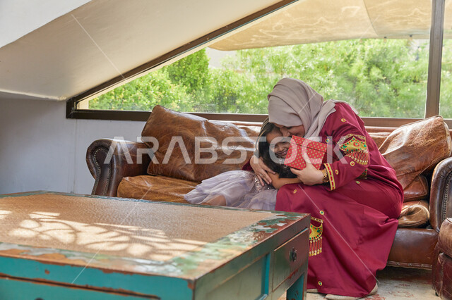 التربيه الصالحة وإنشاء الأطفال على الحب والعطاء، قضاء الأوقات الممتعه مع الأبناء، فتاة عربيه خليجيه اماراتية تحتفل بعيد الأم وتقدم لوالدتها الهدية، ايماءات تدل على الفرح والسعلاده، الإحتفال سويا في الأعياد والمناسبات.