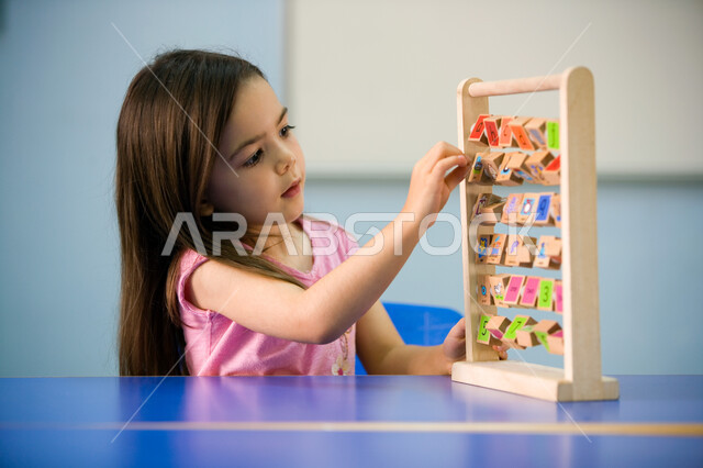 أساليب التعليم الحديثة والمتطورة, التعلم عن طريق اللعب, صورة مقربة لفتاة عربية خليجية إماراتية ترتدي الزي الكاجوال تمسك الأباكوس, مفهوم الحساب الذهني وتنمية المهارات الحسابية لدى الأبناء, اتباع نظام المونتسوري خلال الفصل االدراسي