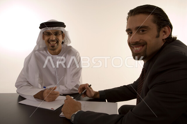مناقشة وتنظيم العمل, الشراكة والتعاون في انجاز العمل, توسيع نطاق الاعمال, إعداد خطط الاعمال الاستراتيجية, مهن ووظائف اماراتية, رجل عربي خليجي اماراتي يرتدي الكندورة الاماراتية ورجل بالبدلة الرسمية في غرفة الإجتماعات داخل مقر الشركة