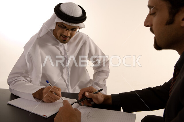 مناقشة وتنظيم العمل, الشراكة والتعاون في انجاز العمل, توسيع نطاق الاعمال, إعداد خطط الاعمال الاستراتيجية, مهن ووظائف اماراتية, رجل عربي خليجي اماراتي يرتدي الكندورة الاماراتية ورجل بالبدلة الرسمية في غرفة الإجتماعات داخل مقر الشركة