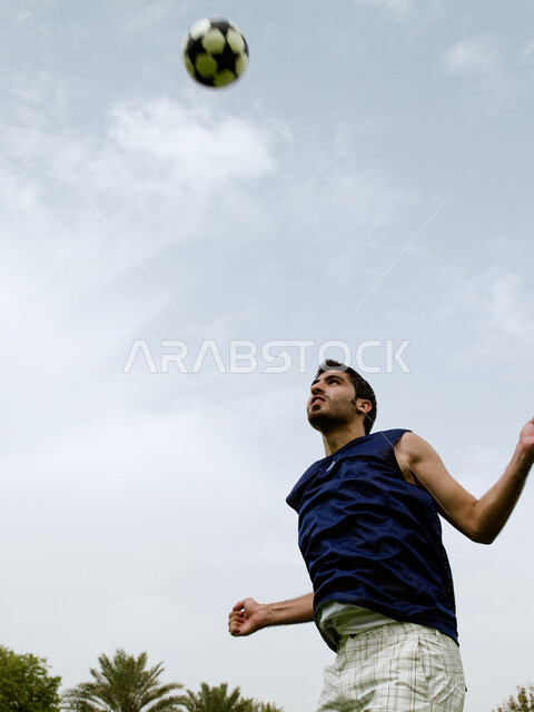 Recreational activities and youth sports, a close-up of an Arab Emirati man playing football, enthusiasm and passion to shoot goals, jump high to kick and shoot the ball, basic skills in playing football, practicing his favorite hobby in the garden.