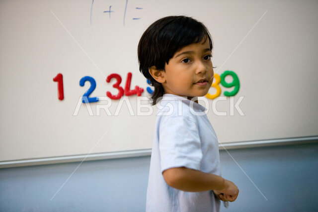 Developing intellectual abilities and arithmetic skills for preparatory stage students, doing arithmetic operations in mathematics, the quality of education in the United Arab Emirates, a picture from the side of an Arab Gulf Emirati student wearing casua