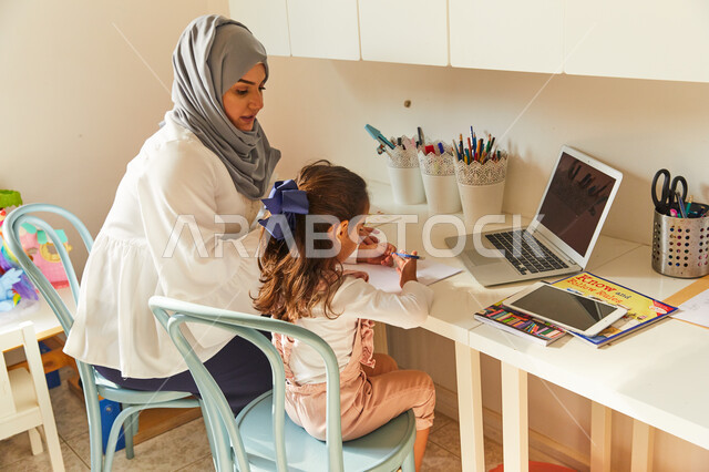 متابعة منصات التعليم الالكتروني المتاحة عبر الانترنت بإستخدام اجهزة الحاسب و التابلت، دمج التعليم مع التقنية والتكنولوجيا، حل الواجبات المنزليه، معلمة خصوصي لمتابعة الدروس في المنزل، أم عربية خليجة اماراتية محجبة تقوم بتعليم وتدريس ابنتها 