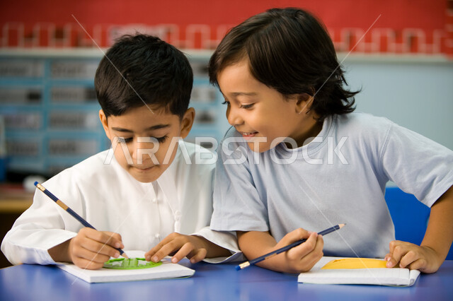 استخدام الأدوات الهندسية وتنمية مهارة الابتكار، صورة مقربة لتلميذين عربيين خليجين اماراتيين يرتديان الزي الكاجوال الاماراتي, تعلم الأشكال الهندسية وطريقة رسمها, تطور وسائل التعليم في الإمارات، الاستمتاع بالنشاطات الجماعية لطلاب التمهيدي