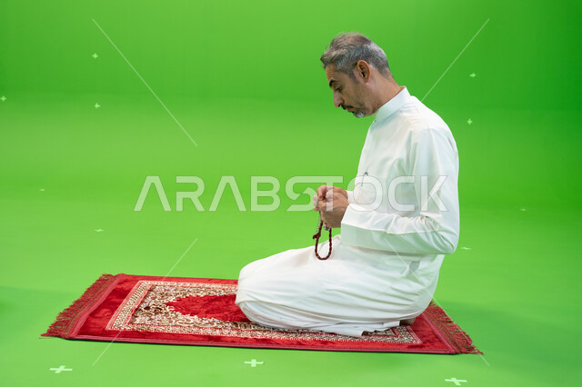 أدعية وأذكار إسلامية، التسبيح وذكر الله تعالى، كروما لرجل عربي خليجي سعودي يرتدي  الثوب التقليدي يحمل بيده السبحة ويجلس على سجادة الصلاة، العبادة والتقرب إلى الله، إسلاميات وعبادة، خلفية خضراء