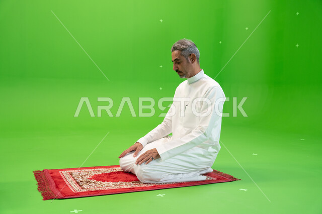 مفهوم أركان الإسلام، أداء الفرائض الدينية، كروما لرجل عربي خليجي سعودي يرتدي الزي التقليدي يجلس على سجادة الصلاة ،العبادة والتقرب إلى الله ،خلفية خضراء