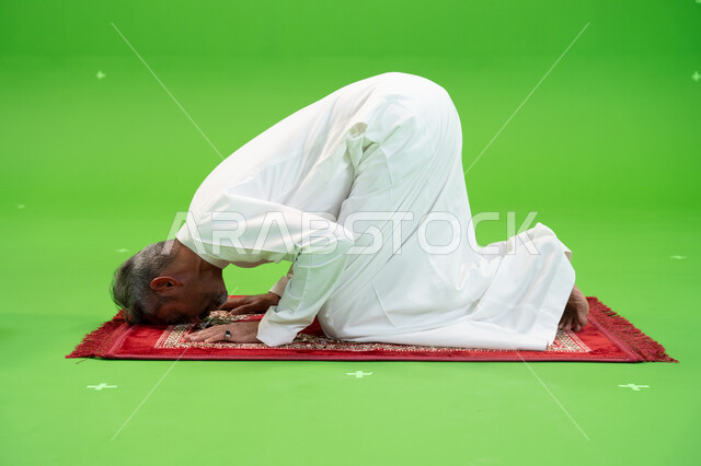 التضرع والخشوع أثناء السجود، إصلاح النفس بالتذلل لرب العالمين، أداء الفرائض الدينية، مفهوم أركان الإسلام، كروما لرجل عربي خليجي سعودي يرتدي الزي التقليدي يجلس على سجادة الصلاة ،العبادة والتقرب إلى الله، صورة الجسم بالطول الكامل ،خلفية خضراء