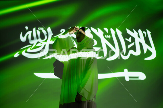 اندماج ضوء العلم مع الجسم، إيماءات المعاينه و التدقيق عن بعد، الاحتفال بيوم العلم 11مارس والعيد الوطني، أعياد ومناسبات وطنية، صورة لامرأة عربية خليجية سعودية محجبة ترتدي العباءة تضع يديها فوق عينيها وتنظر إلى شيء ما, ذكرى اليوم الوطني السعودي 23 سبتمبر