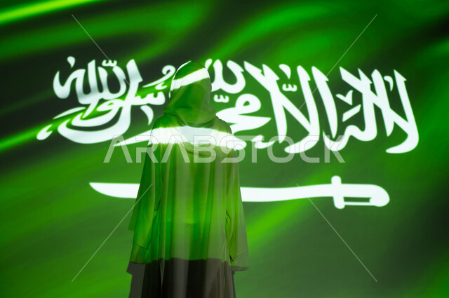 مشاعر الحب والولاء والانتماء للمملكة، انعكاس ضوء العلم على الجسم، يوم العلم 11 مارس، احتفالات ومناسبات وطنية ، صورة من الخلف لامرأة عربية خليجية محجبة ترتدي العباءة، الاحتفال بذكرى اليوم الوطني السعودي 23 ستمبر و العيد الوطني، اظهار التفاني والفخر للبلاد
