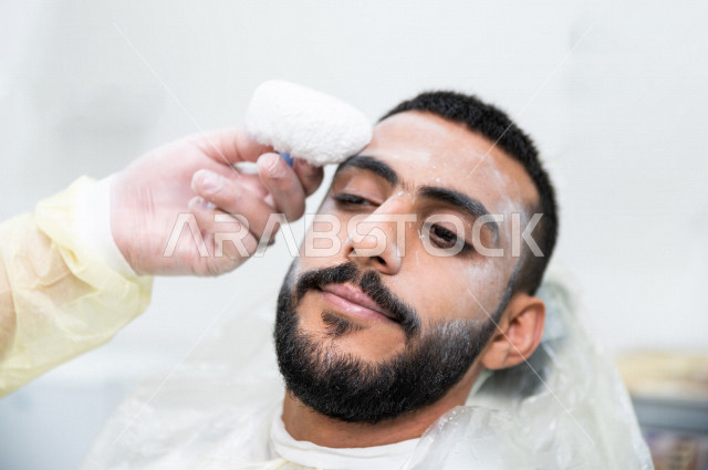 رجل سعودي خليجي في زيارة لصالون الحلاقة ، ازالة شعرالوجه باستخدام تقنية الخيط ، العناية بالمظهر الخارجي 