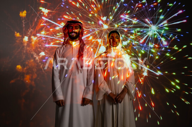 المفرقعات والألعاب النارية في الأعياد والمناسبات الوطنية، النظر الى الكاميرا بإيماءات السعادة، زوجان عربيان خليجيان سعوديان يحتفلان بالأفراح السعيدة، مفهوم حب الوطن والانتماء إليه، مشاركة العائلة باللحظات والذكريات السنوية،انشطة ترفيهية في العيد الإسلامي .