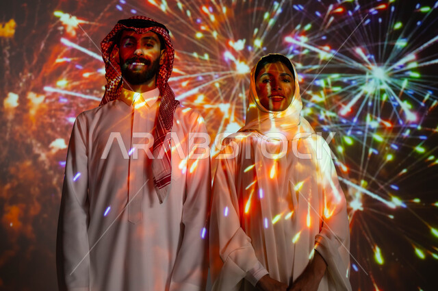 مشاركة العائلة باللحظات والذكريات السنوية، المفرقعات والألعاب النارية في الأعياد والمناسبات الوطنية، النظر الى الكاميرا بإيماءات السعادة، زوجان عربيان خليجيان سعوديان يحتفلان بالأفراح السعيدة، مفهوم حب الوطن والانتماء إليه، انشطة ترفيهية في العيد الإسلامي .