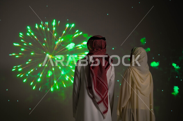 الحفاظ على الهوية الوطنية و الاعتزاز والفخر بتراثها، التعبير عن الحب والولاء للبلاد ،الاستمتاع بالألعاب النارية في المناسبات والأعياد الشعبيه، صورة من الخلف لزوجين عربيين خليجيين سعوديين يحتفلان بذكرى اليوم الوطني السعودي في23 سبتمبر والعيد الوطني