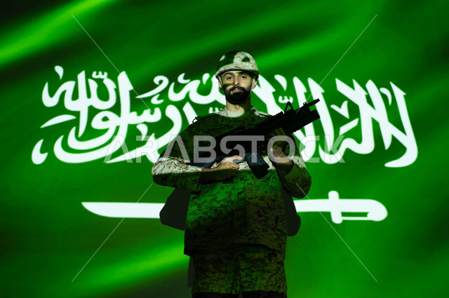 يوم العلم 11 مارس، تعزيز القوات العسكرية لزيادة الأمن والحماية والاستقرار في المملكة العربية السعودية، الاحتفال بذكرى اليوم الوطني 23 سبتمبر والعيد الوطني، اندماج صورة العلم مع جسم الشاب ، جندي عربي خليجي يرتدي الزي العسكري والخوذة يحمل السلاح.