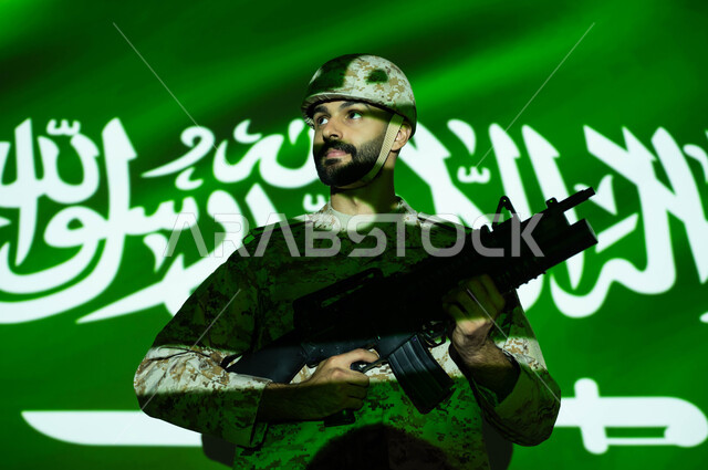 الاحتفال بذكرى اليوم الوطني 23 سبتمبر والعيد الوطني، تعزيز القوات العسكرية لزيادة الأمن والحماية والاستقرار في المملكة العربية السعودية، انعكاس ضوء العلم على جسم الشاب ، يوم العلم 11 مارس، صورة مقربة لجندي عربي خليجي يرتدي الزي العسكري والخوذة يحمل السلاح.