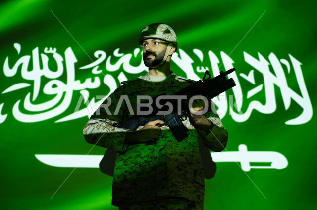 تعزيز القوات العسكرية لزيادة الأمن والحماية والاستقرار في المملكة العربية السعودية، الاحتفال بذكرى اليوم الوطني 23 سبتمبر والعيد الوطني، انعكاس ضوء العلم على جسم الشاب ، يوم العلم 11 مارس، جندي عربي خليجي يرتدي الزي العسكري والخوذة يحمل السلاح.