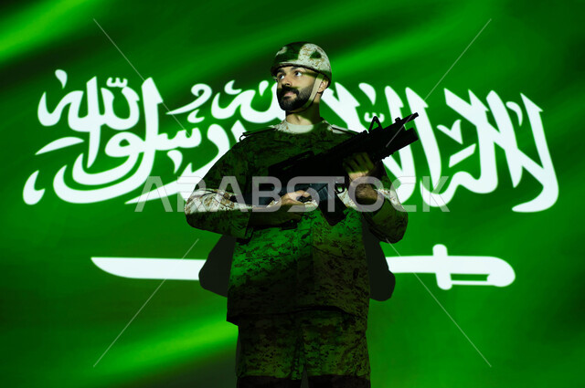 يوم العلم 11 مارس، تعزيز القوات العسكرية لزيادة الأمن والحماية والاستقرار في المملكة العربية السعودية، الاحتفال بذكرى اليوم الوطني السعودي 23 سبتمبر والعيد الوطني، اندماج صورة العلم مع جسم الشاب ، جندي عربي خليجي يرتدي الزي العسكري والخوذة يحمل السلاح.