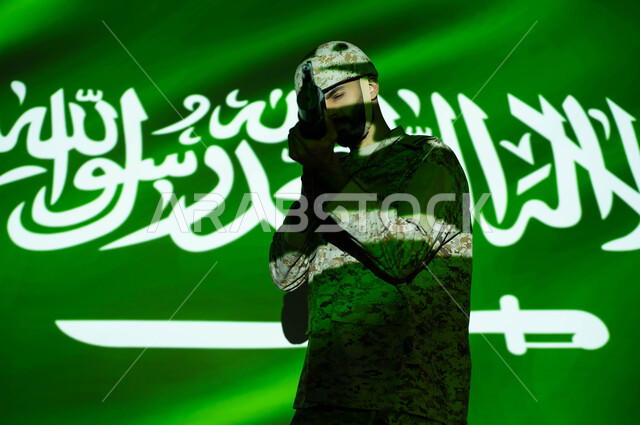 تعزيز القوات العسكرية لزيادة الأمن والحماية والاستقرار في المملكة العربية السعودية، الاحتفال بذكرى اليوم الوطني 23 سبتمبر والعيد الوطني، انعكاس ضوء العلم على جسم الشاب، يوم العلم 11 مارس، جندي عربي خليجي يرتدي الزي العسكري والخوذة يحمل السلاح.