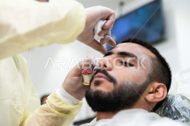 رجل سعودي خليجي في زيارة لصالون الحلاقة ، ازالة شعرالوجه باستخدام تقنية الخيط ، العناية بالمظهر الخارجي 