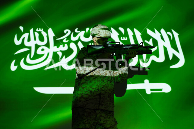 الاحتفال بذكرى اليوم الوطني 23 سبتمبر والعيد الوطني، انعكاس ضوء علم المملكة على جسد الشاب، يوم العلم 11 مارس، جندي عربي خليجي سعودي يرتدي الزي العسكري والخوذة يحمل السلاح، حفظ الأمن والاستقرار بقوات الجيش السعودي، حب الوطن والدفاع عنه