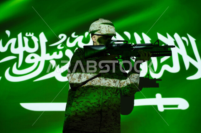 الاحتفال بذكرى اليوم الوطني 23 سبتمبر والعيد الوطني، انعكاس ضوء علم المملكة على جسد الشاب، يوم العلم 11 مارس، جندي عربي خليجي سعودي يرتدي الزي العسكري والخوذة يحمل السلاح، حفظ الأمن والاستقرار بقوات الجيش السعودي، حب الوطن والدفاع عنه