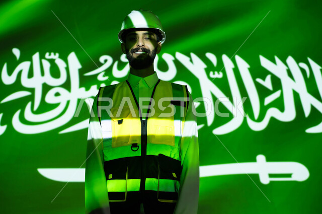 Engineering development and development of the construction sector with the hands of the people of the country, looking at the camera, a smiling Saudi Gulf Arab engineer wearing a jacket and a protective helmet, immersing the body in the light of science, Science Day, March 11, celebrating the anniversary of the Saudi National Day, September 23, and National Day, Saudi professions and jobs
