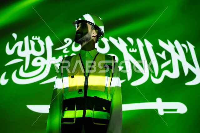 Engineering development and development of the construction sector with the help of the people of the nation, a smiling Saudi Gulf Arab engineer wearing a jacket and a protection helmet, the body immersed in the light of science, Science Day, March 11, celebrating the anniversary of the Saudi National Day, September 23, and National Day, Saudi professions and jobs.