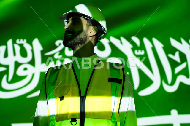 Developing the construction sector and engineering development with the help of the people of the nation, a close-up of a smiling Saudi Gulf Arab engineer wearing a jacket and a protection helmet, the body immersed in the light of science, Science Day, March 11, celebrating the anniversary of the Saudi National Day, September 23, and National Day