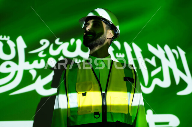 Developing the construction sector and engineering development with the help of the people of the nation, a close-up of a smiling Saudi Gulf Arab engineer wearing a jacket and a protection helmet, the body immersed in the light of science, Science Day, March 11, celebrating the anniversary of the Saudi National Day, September 23, and National Day