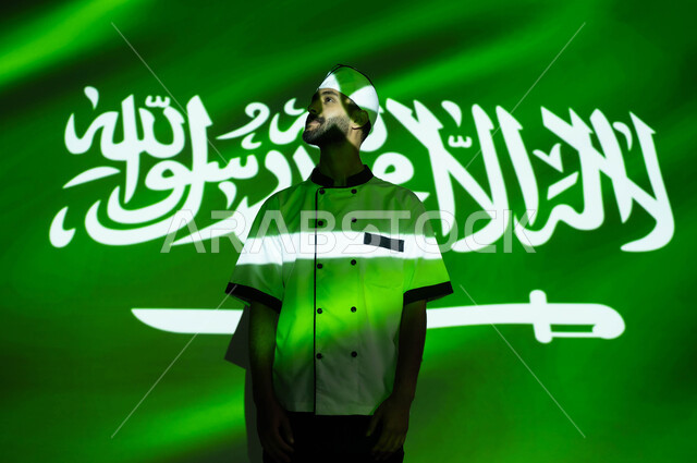 Looks of pride and pride in the country, the development and renaissance of the country in the various Saudi professions, the celebration of the Saudi National Day, Rabi’ al-Awwal 8, Flag Day, March 11, a smiling Saudi Arabian Gulf chef wearing a chef’s uniform on National Day, the fusion of the face in the light of knowledge, love and loyalty to the homeland.