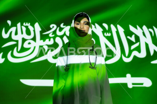 توفير الخدمات العلاجية والرعاية الصحية لأبناء الوطن، اليوم الوطني السعودي 23 سبتمبر، اندماج الوجه مع ضوء العلم، طبيبة عربية خليجية سعودية محجبة ترتدي المعطف الطبي ، الاحتفال بيوم العلم السعودي 11 مارس والعيد الوطني، مهن ووظائف نسائية