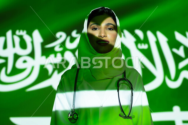انعكاس ضوء العلم على الوجه، تقديم الرعاية الصحية لأبناء الوطن، صور مقربة لطبيبة عربية خليجية سعودية مبتسمة محجبة ترتدي المعطف الطبي، اليوم الوطني السعودي 23 سبتمبر، الاحتفال بيوم العلم السعودي 11 مارس والعيد الوطني، مهن ووظائف نسائية
