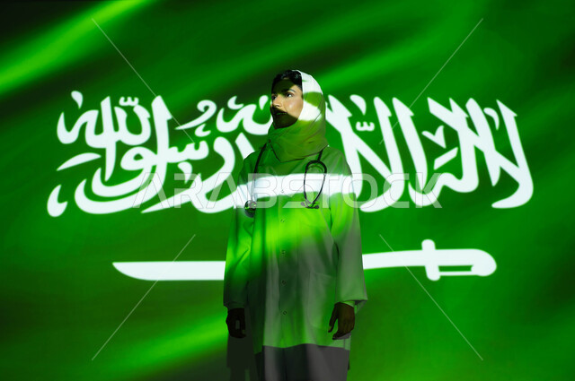 تقديم الخدمات العلاجية والرعاية الصحية لأبناء الوطن، انعكاس ضوء العلم على وجه طبيبة عربية خليجية سعودية محجبة ترتدي المعطف الطبي ، اليوم الوطني السعودي 23 سبتمبر، الاحتفال بيوم العلم السعودي 11 مارس والعيد الوطني، مهن ووظائف نسائية