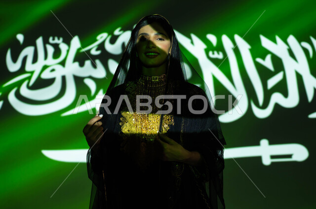 Love and loyalty to the Kingdom, Flag Day, March 11, celebration of the Saudi National Day, September 23, a close-up of a smiling Saudi Gulf Arab woman wearing the sheila and the central region’s dress on National Day, national celebrations and events, immersing the body in the light of science, Founding Day 1727 AD