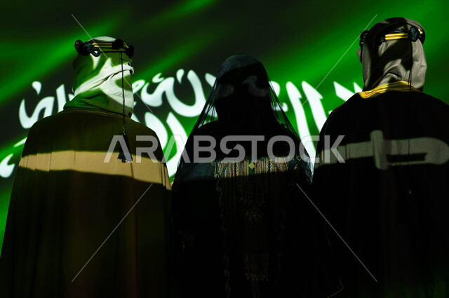  الإحتفال بالمناسبات و الاعياد وذكرى اليوم الوطني السعودي 23 سبتمبر، انعكاس ضوء العلم على الجسم، صورة من الخلف لمواطنين عرب خليجيين سعوديين يرتدون الزي التقليدي الشعبي، يوم العلم 11 مارس، مشاعر الحب والولاء والانتماء للمملكة، تأسيس الدولة السعودية الاولى 1727 م