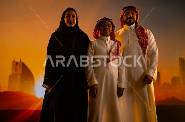الإنشاءات والهندسة المعمارية، عائلة عربية خليجية سعودية تقف بثقة وتنظر إلى الكاميرا، النمو والتطور العمراني في مدينة الرياض، مفهوم الترابط الأسري، رؤية السعودية المستقبلية 2030، خلفية الأبراج وناطحات السحاب في السعودية وقت غروب الشمس