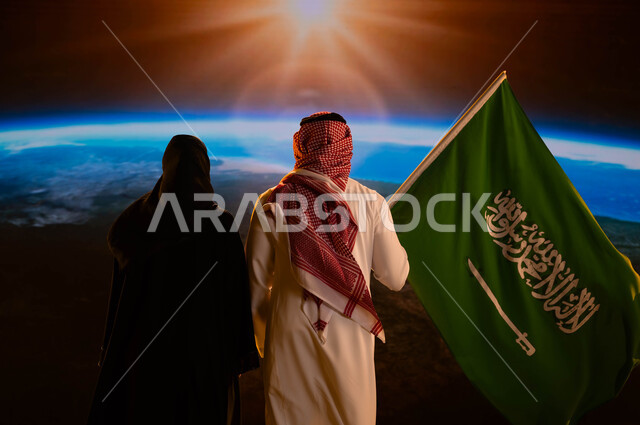 الفخر والاعتزاز بالوطن، العيد الوطني 23 سبتمبر، صورة من الخلف لزوجان عربيان خليجيان سعوديان، يوم العلم السعودي 11 مارس، رجل يرتدي الزي السعودي التقليدي ويحمل علم المملكة إحتفالا باليوم الوطني لتوحيد السعودية، شروق الشمس على كوكب الأرض