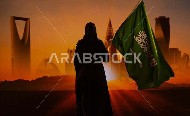 يوم العلم السعودي 11 مارس، صورة من الخلف لإمرأة عربية خليجية سعودية محجبة ترتدي العباءة وتحمل علم المملكة وتقف امام أبراج وناطحات سحاب مدينة الرياض وقت شروق الشمس، العيد الوطني 23 سبتمبر، اليوم الوطني السعودي، النمو والتطور العمراني في السعودية