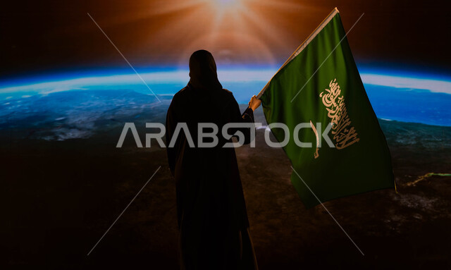 الاحتفال بيوم العلم 11 مارس، ذكرى اليوم الوطني السعودي، صورة من الخلف لامرأة سعودية عربية خليجية محجبة تحمل العلم السعودي وتنظر الى كوكب الارض، العيد الوطني السعودي 8 ربيع الأول، رحلة السعودية للفضاء الخارجي، التباهي والتفاخر بإنجازات الوطن