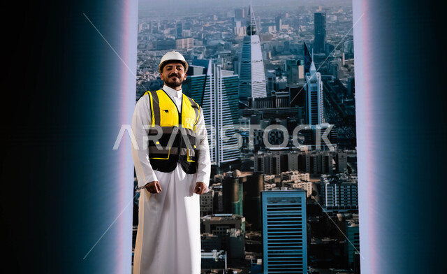الأبراج و الإنجازات العمرانية في الرياض التي تحققت بفضل مهندسي الوطن, إيماءات الافتخار بالنهضة العمرانية للمملكة, مشاريع هندسية تنموية وطنية سعودية, مهندس عربي سعودي خليجي مبتسم يرتدي الخوذة وسترة الحماية يقف بشموخ, وظائف ومهن سعودية, خلفية أبراج الرياض