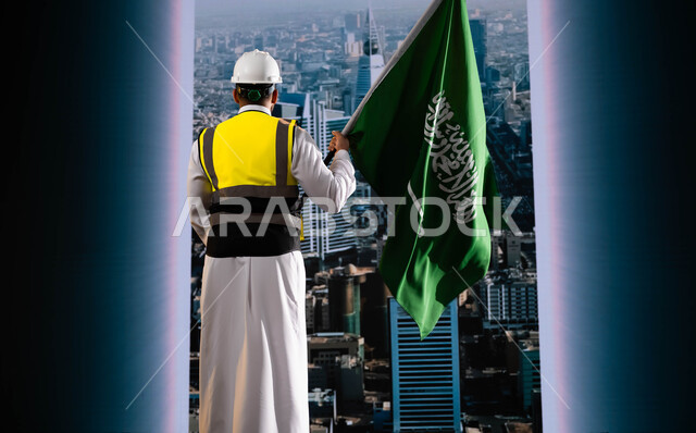 اليوم الوطني لذكرى توحيد السعودية, تخليد تاريخ العيد الوطني السعودي 23 سبتمبر, الاحتفال بيوم العلم 11 مارس, صورة من الخلف لمهندس عربي سعودي خليجي يرتدي الخوذة وسترة الحماية ويمسك علم المملكة ويقف امام أبراج الرياض المتميزة, نهضة الوطن بفضل أبنائه
