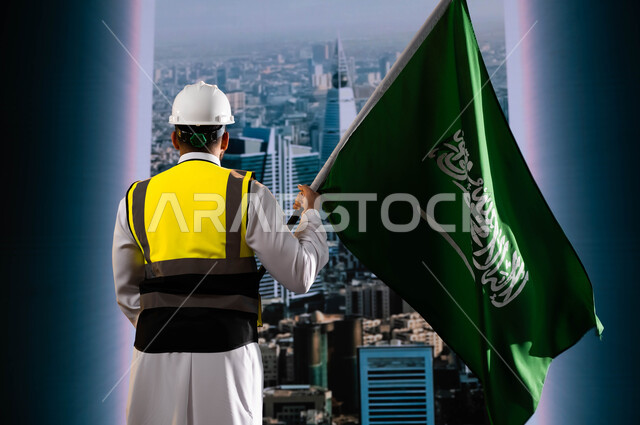اليوم الوطني لذكرى توحيد السعودية, تخليد تاريخ العيد الوطني 23سبتمبر, الاحتفال بيوم العلم 11 مارس, صورة من الخلف لمهندس عربي سعودي خليجي يرتدي الخوذة وسترة الحماية ويمسك علم المملكة ويقف امام أبراج وناطحات سحاب الرياض المتميزة, نهضة الوطن بفضل أبنائه